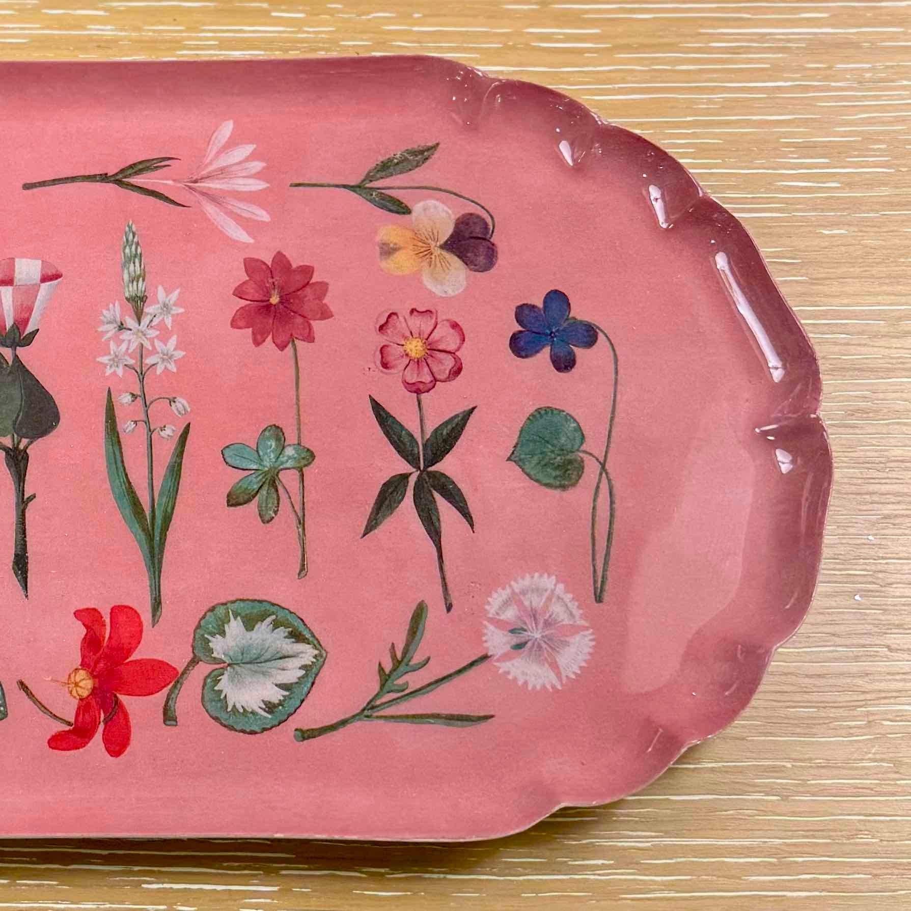 Pink tray with floral designs on a textured surface