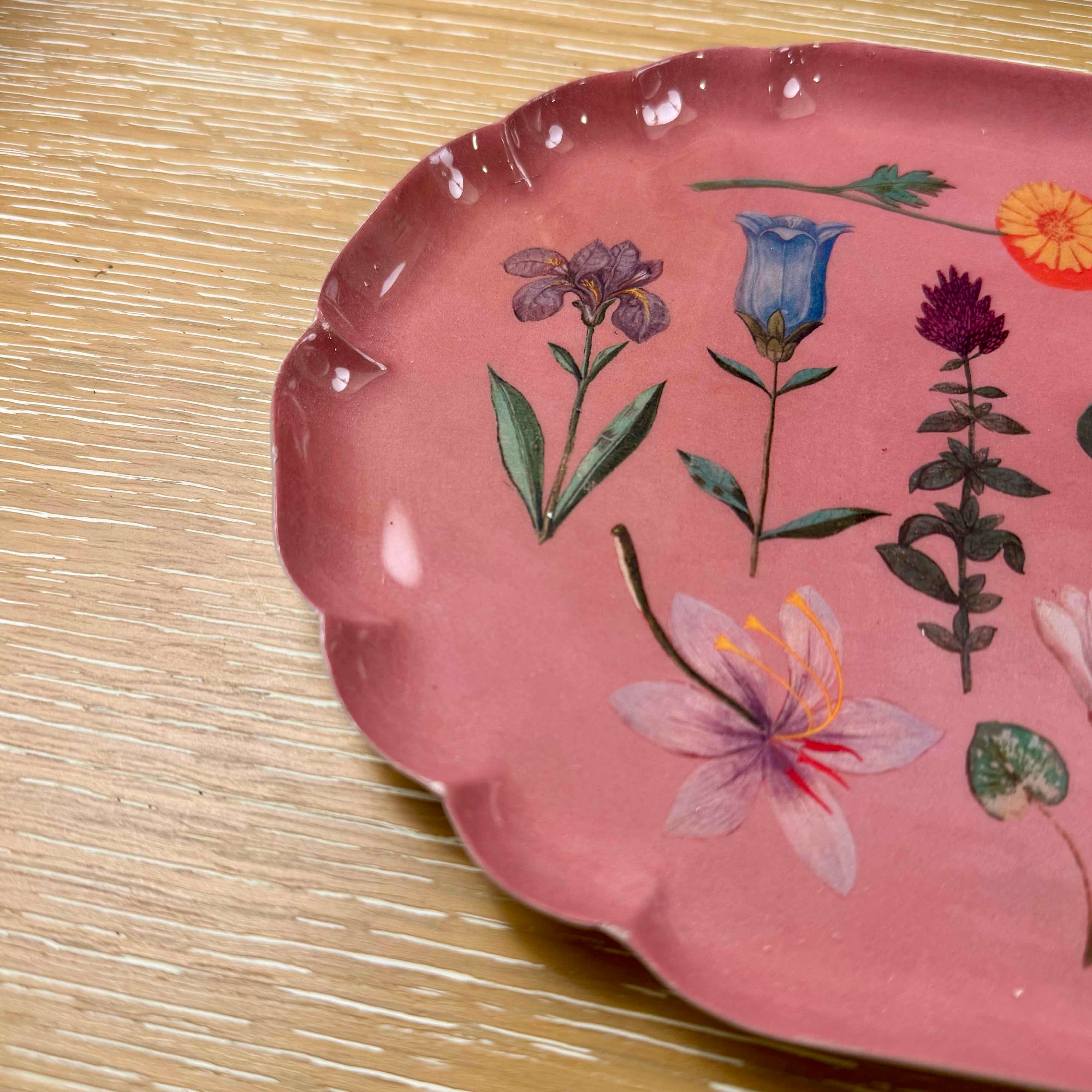 Pink ceramic plate with floral designs on a wooden surface
