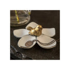 Decorative item with a gold bird and white flower-shaped base on a dark surface