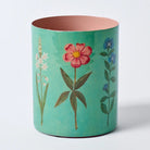 Decorative cylindrical container with floral designs on a light blue background