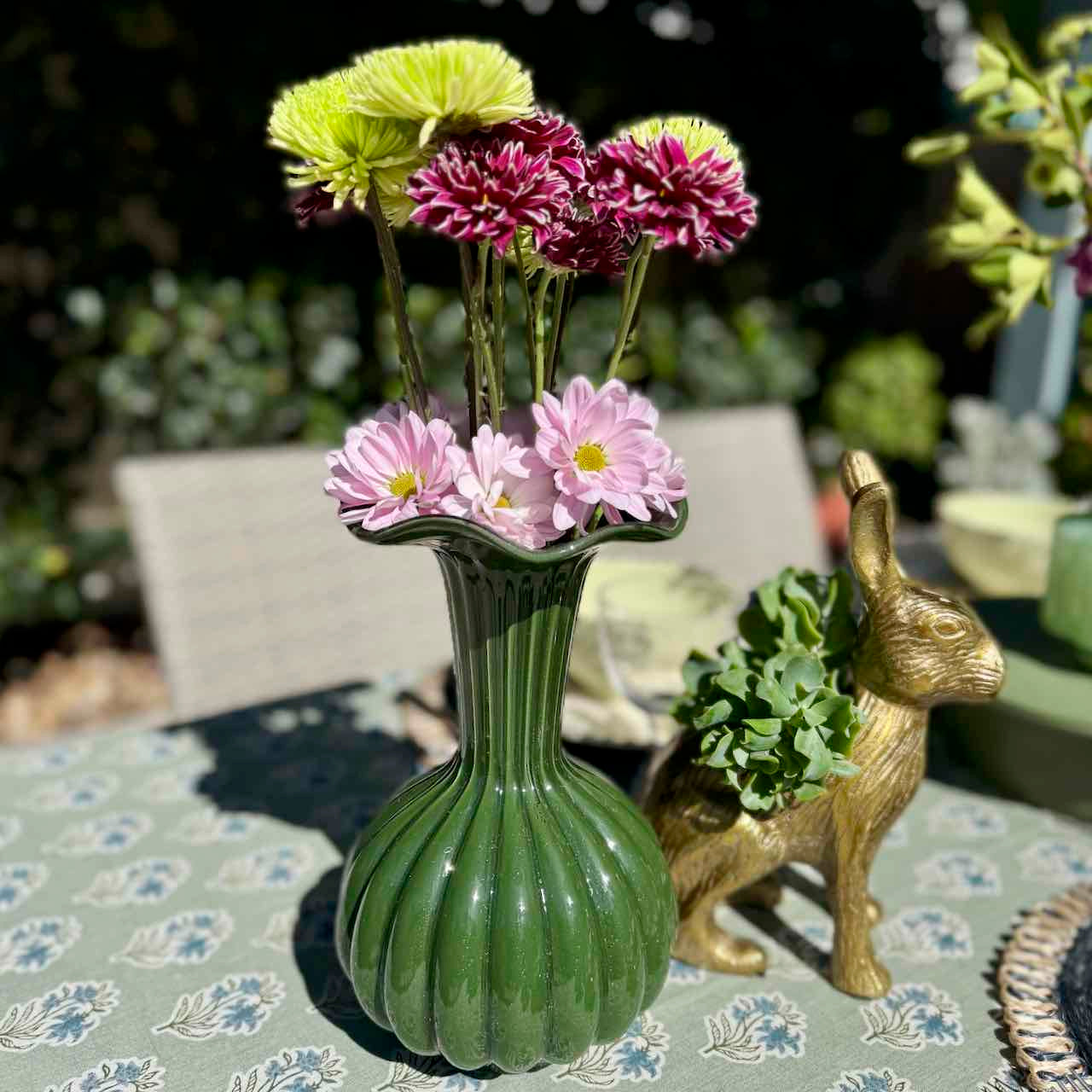 Green vase with flowers on a table outdoors