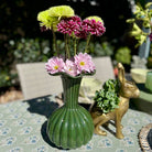 Green vase with flowers on a table outdoors