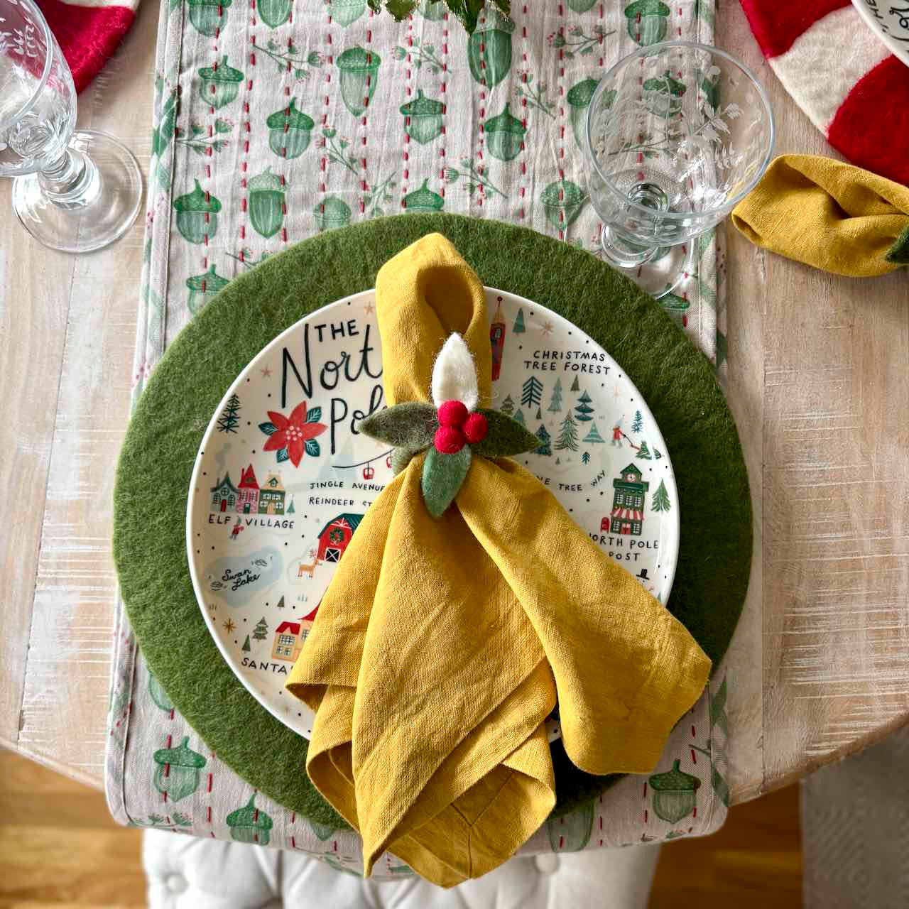 Christmas-themed table setting with a plate, green charger, and yellow napkin.