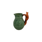 Green ceramic pitcher with a wooden handle shaped like a fox on a white background