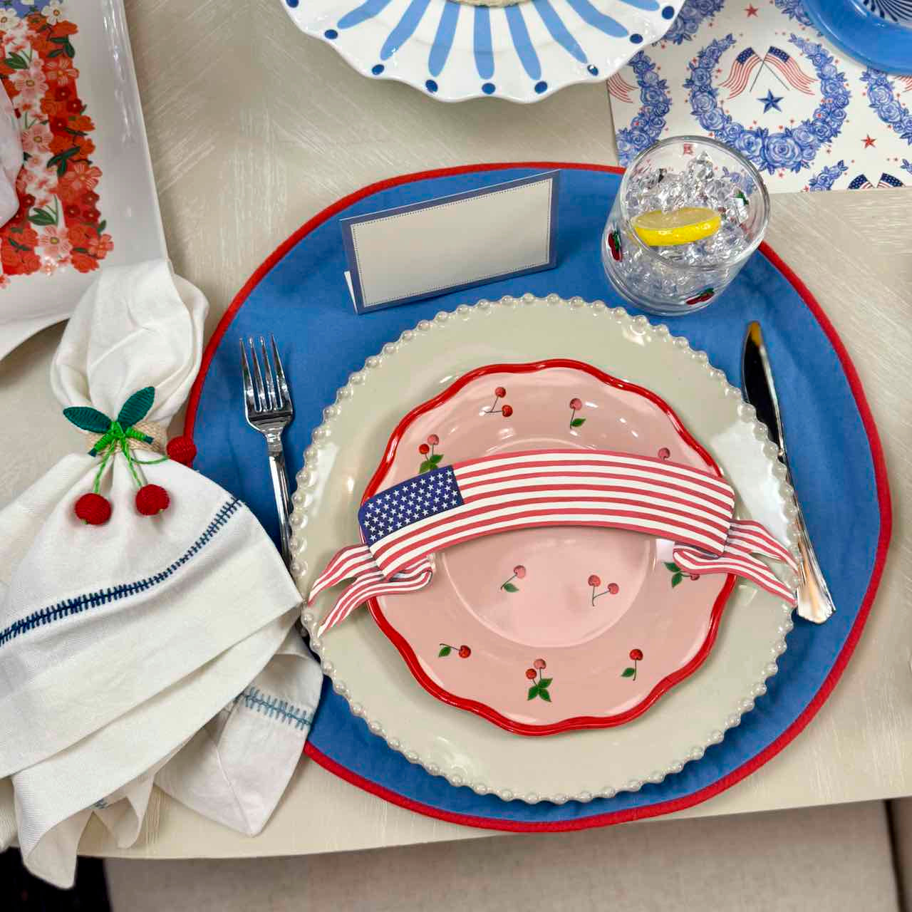 Table setting with decorative plates, napkin, and cutlery on a white tablecloth.
