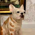 Ceramic statue of a dog with a brown and white color pattern on a decorative background.