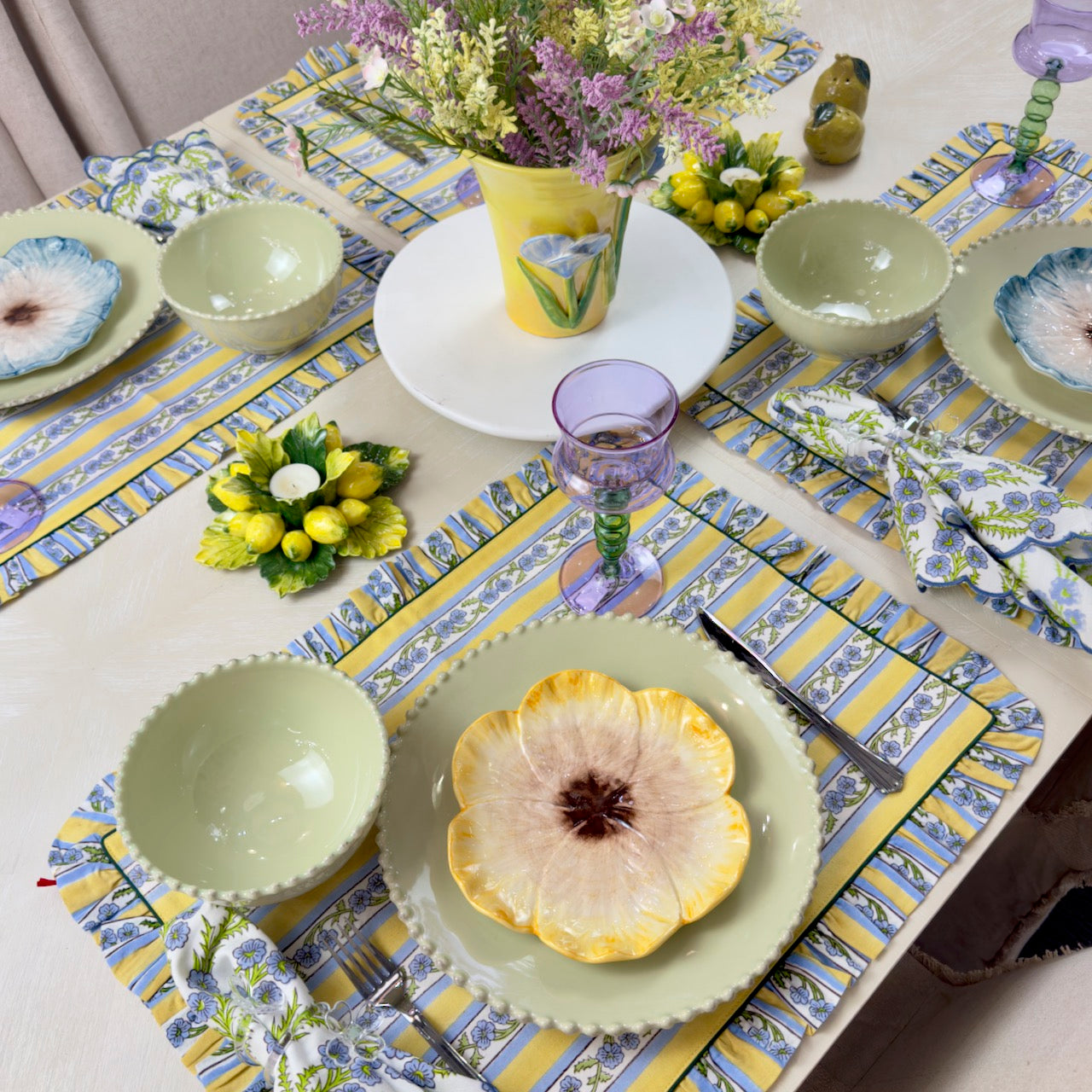 Decorative table setting with floral tablecloth, plates, and cutlery.