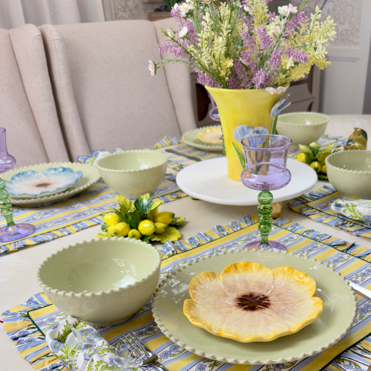 Dining table set with floral centerpieces, plates, and bowls on a patterned tablecloth.