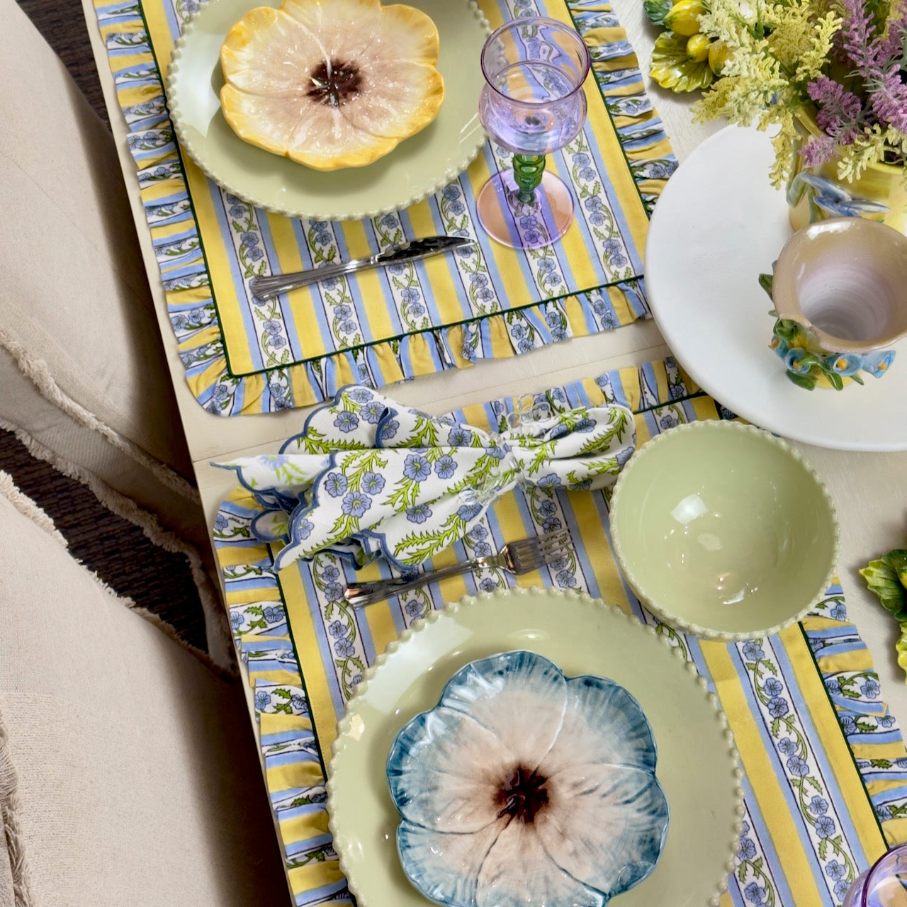 Decorative table setting with floral plates, napkins, and striped placemats.