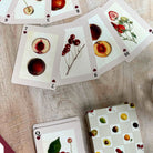 Playing cards with fruit and floral designs on a wooden surface
