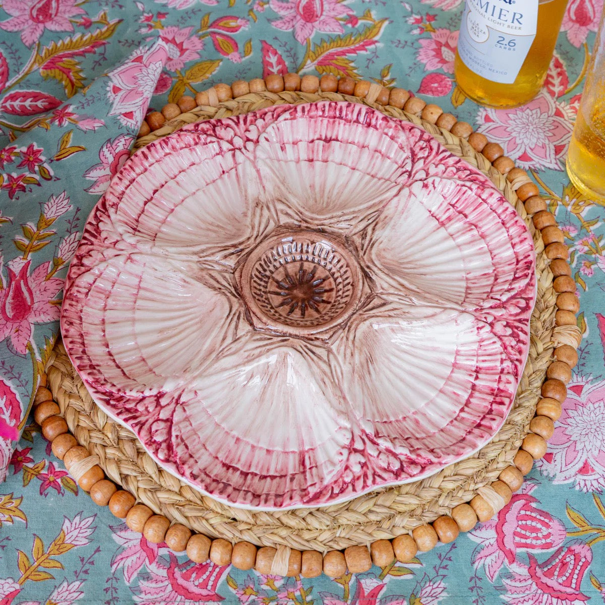 Pink and white ceramic plate with wicker rim on a floral tablecloth
