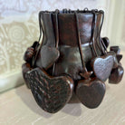 Decorative metal holder with heart designs on a textured surface