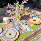 Decorative table setting with floral tablecloth, plates, and flowers.