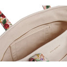 Close-up of a beige handbag with floral patterns on a white background