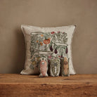 Decorative pillow with a nature-themed design on a wooden surface against a brown background