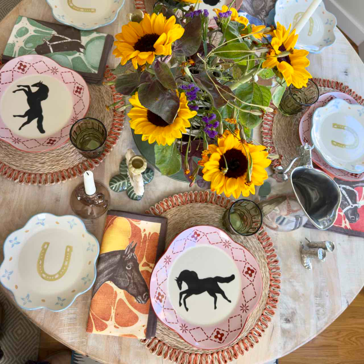 Decorative table setting with horse-themed coasters and sunflowers.