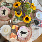 Decorative table setting with horse-themed coasters and sunflowers.
