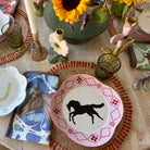 Decorative table setting with horse-themed plates and napkins on a wooden table.