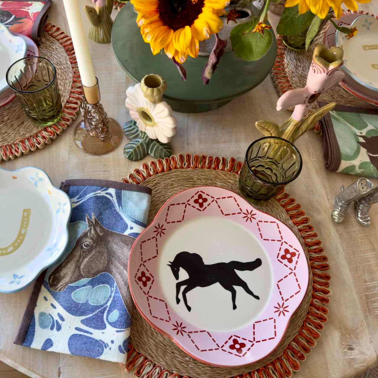 Decorative table setting with horse-themed plates and sunflowers.