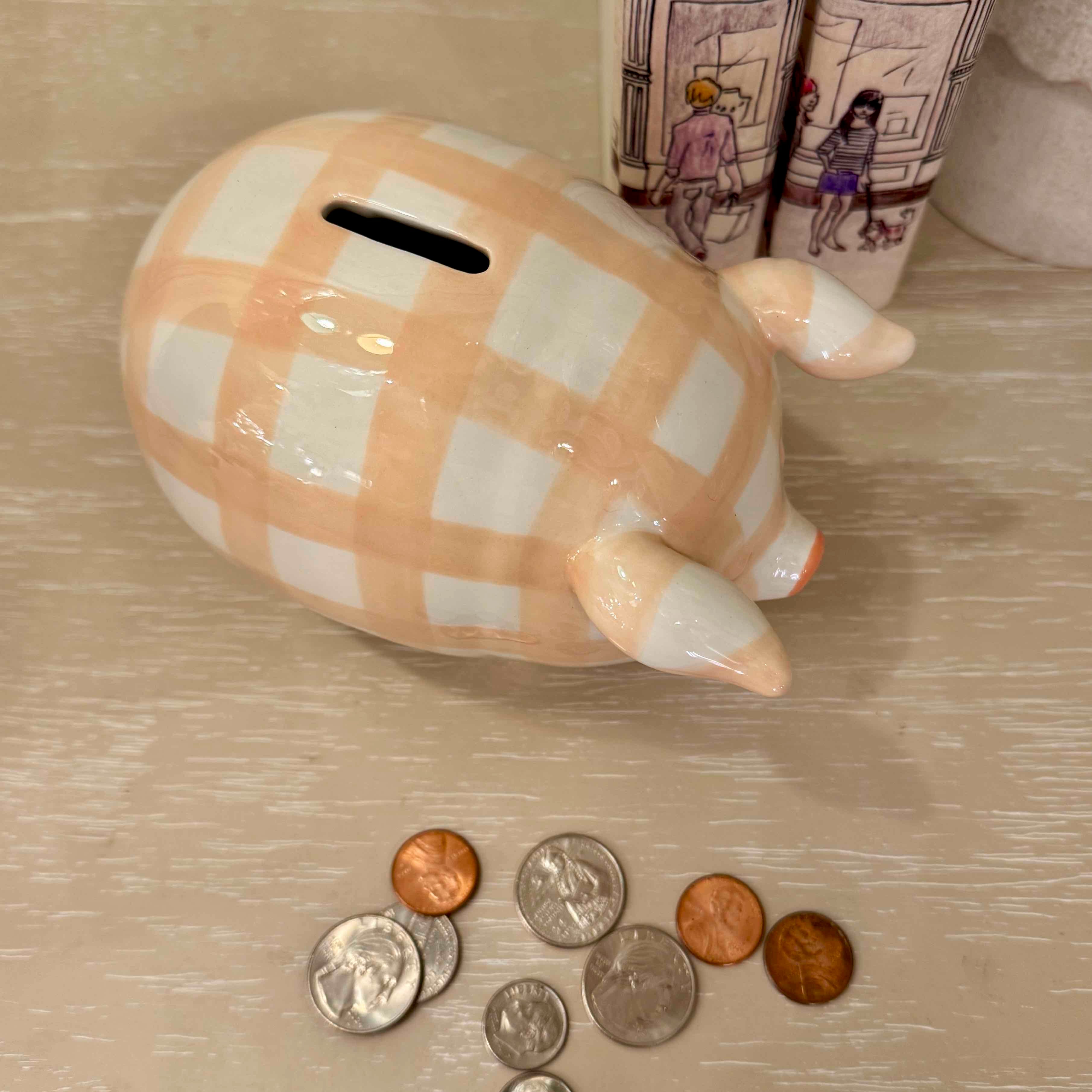Checkered piggy bank with coins on a wooden surface