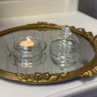 Two glass containers with a lit candle on a decorative mirror