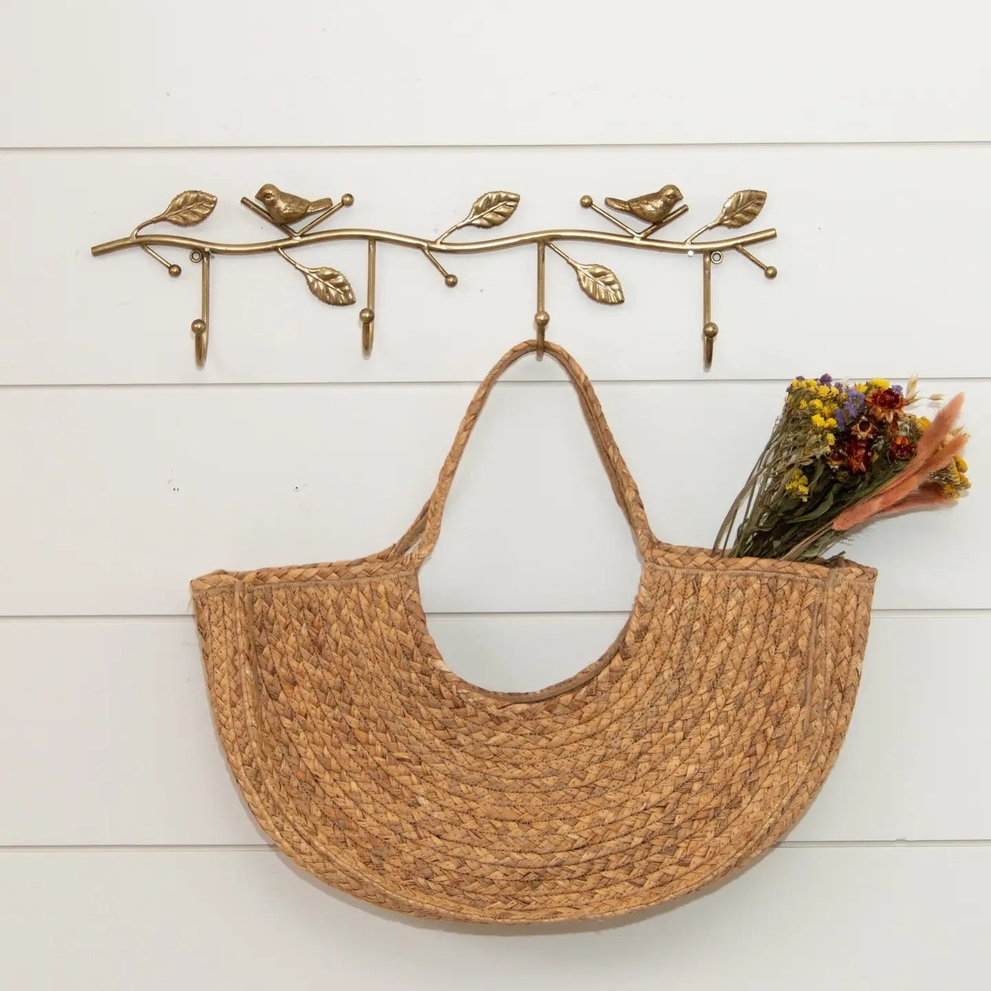 Woven bag hanging on a decorative wall hook with a branch design.