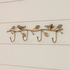 Decorative brass wall hook with birds and leaves on a white background