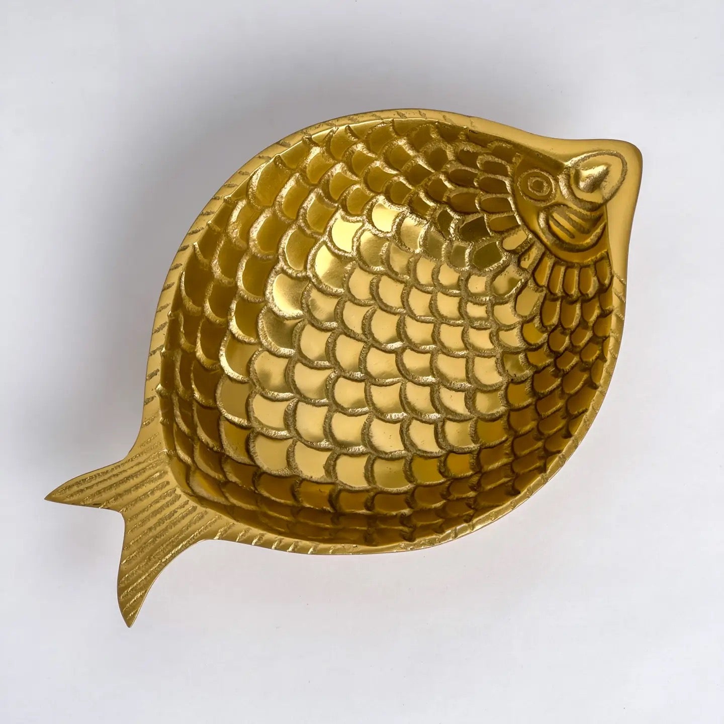 A gold-colored fish-shaped bowl with a detailed scale pattern, photographed on a plain white background.