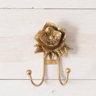 Decorative gold flower-shaped wall hook on a white wooden background