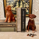 Two ceramic dog figurines on books with a decorative background