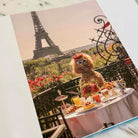 Dog with sunglasses at a Parisian table with Eiffel Tower in the background