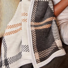 Person wrapped in a plaid blanket with neutral colors