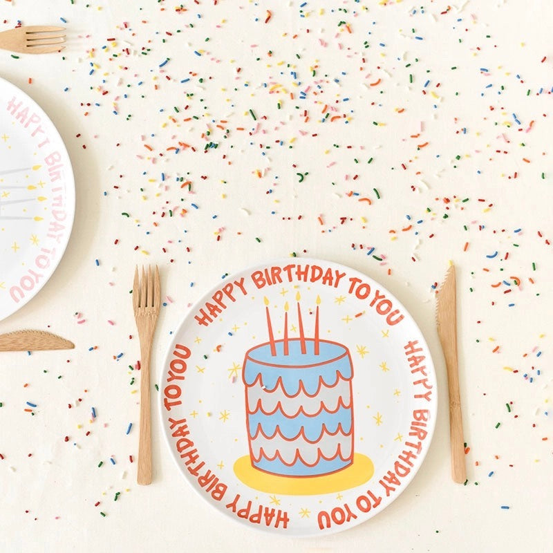 Children's birthday plate with cake design and 'Happy Birthday to You' text on a sprinkled surface.