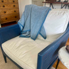 Blue and white patterned blanket draped over a white cushion on a blue chair.