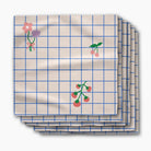 A stack of square paper napkins with a cream background, blue grid lines, and small floral and berry illustrations, shown on a light gray background.