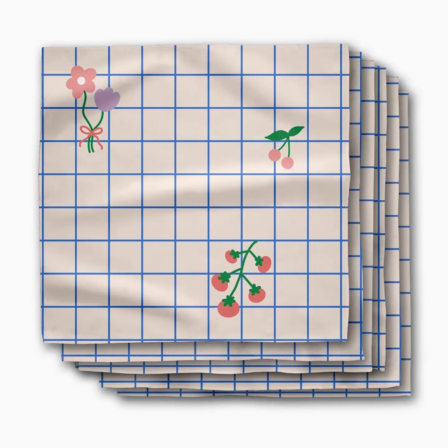 A stack of square paper napkins with a cream background, blue grid lines, and small floral and berry illustrations, shown on a light gray background.