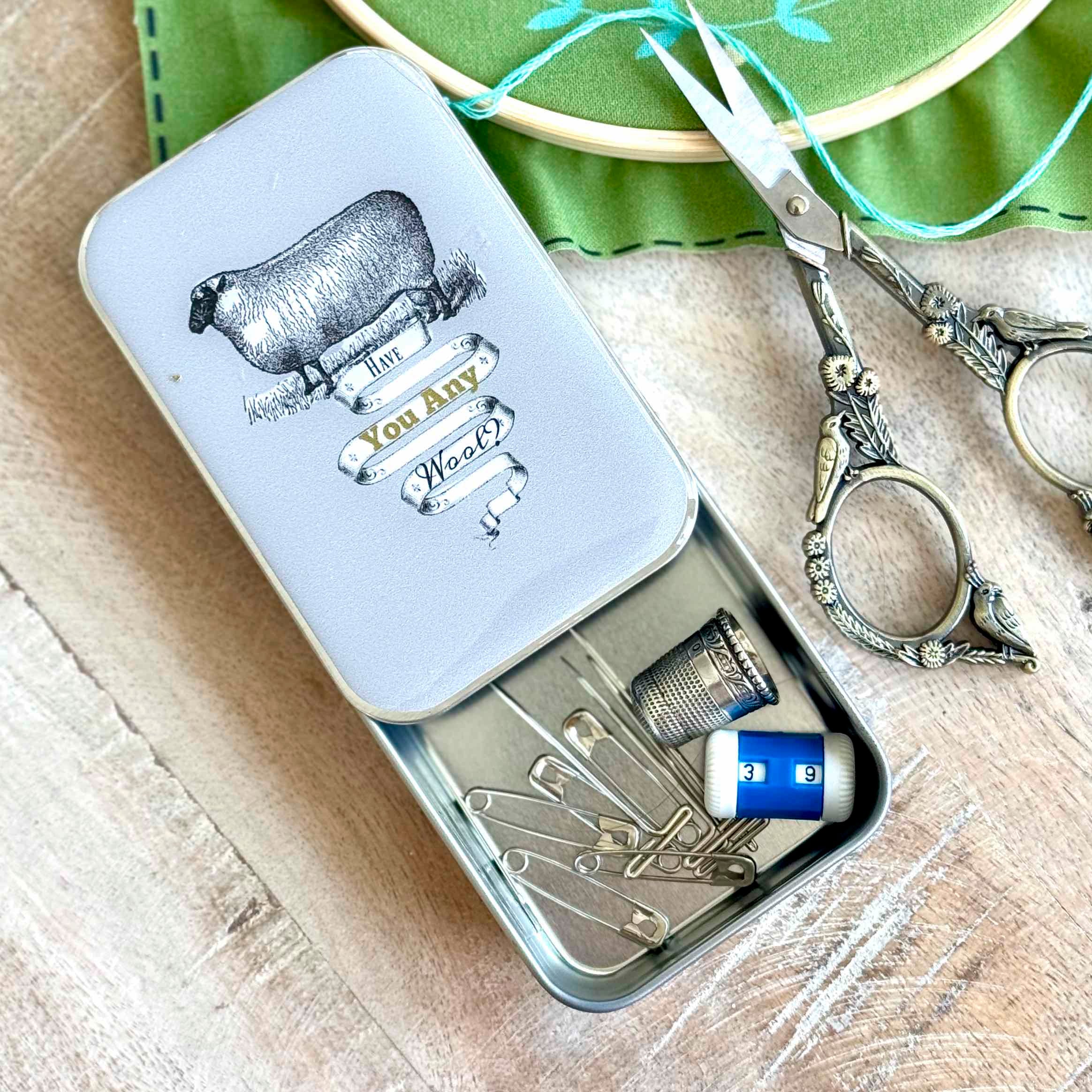 Sewing kit in a tin with scissors on a wooden surface