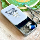 Small metal sewing kit with tools on a wooden surface