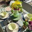 Outdoor table setting with floral arrangements and decorative plates.