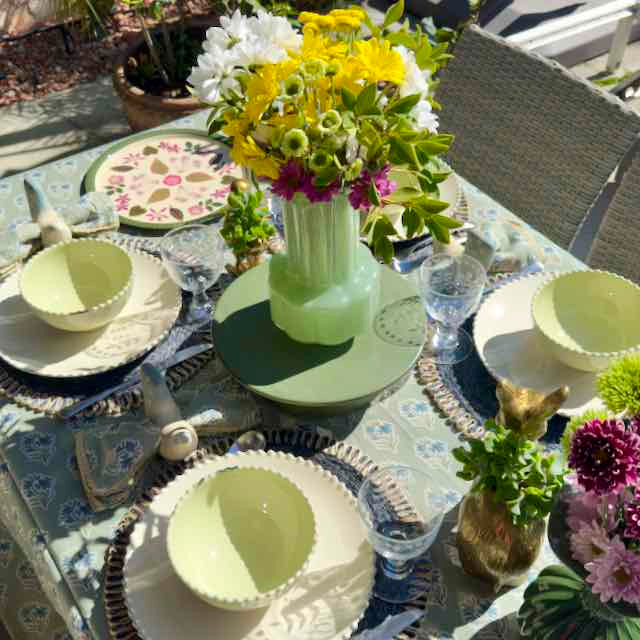 Outdoor table setting with floral arrangements and decorative plates.