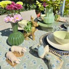 Decorative table setting with floral arrangements, animal figurines, and patterned tablecloth.