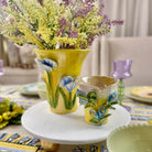 Decorative ceramic items including a yellow vase and small cup with floral designs on a table.