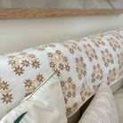 Floral-patterned cushion on a sofa with a wooden headboard in the background