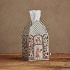 Decorative tissue box cover with animal illustrations on a wooden surface and brown background