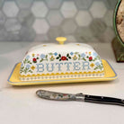 Decorative butter dish with floral patterns and a knife on a kitchen counter.
