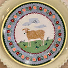 Decorative plate with a sheep illustration and floral design on a beige background