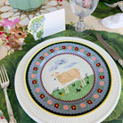Decorative plate with a sheep design on a table setting with cutlery and a mouse figurine.