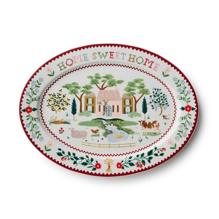 Decorative plate with 'Home Sweet Home' text and a countryside scene on a white background