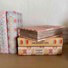 Stack of books with decorative covers on a wooden surface