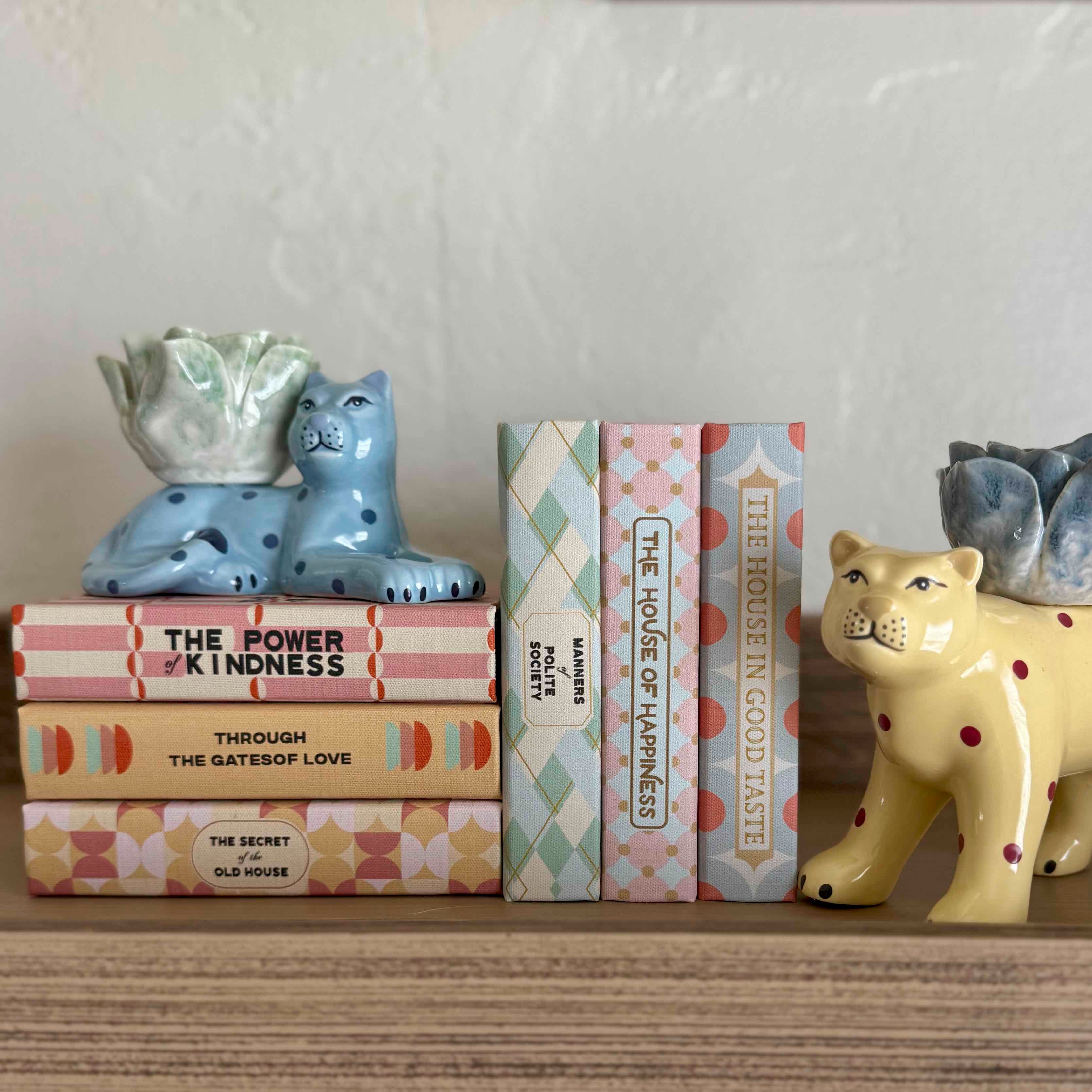 Decorative shelf with animal figurines and books on a neutral background
